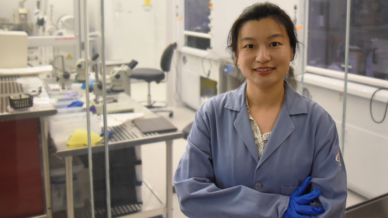 Xiaoyue Ni wearing blue lab coat in her lab