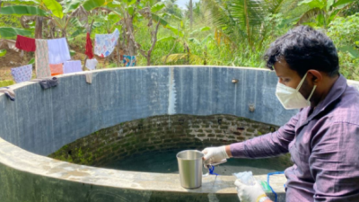 man dipping water from open well in Sri Lanka