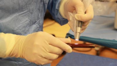 surgeon's hands holding instruments at surgical site in operating room